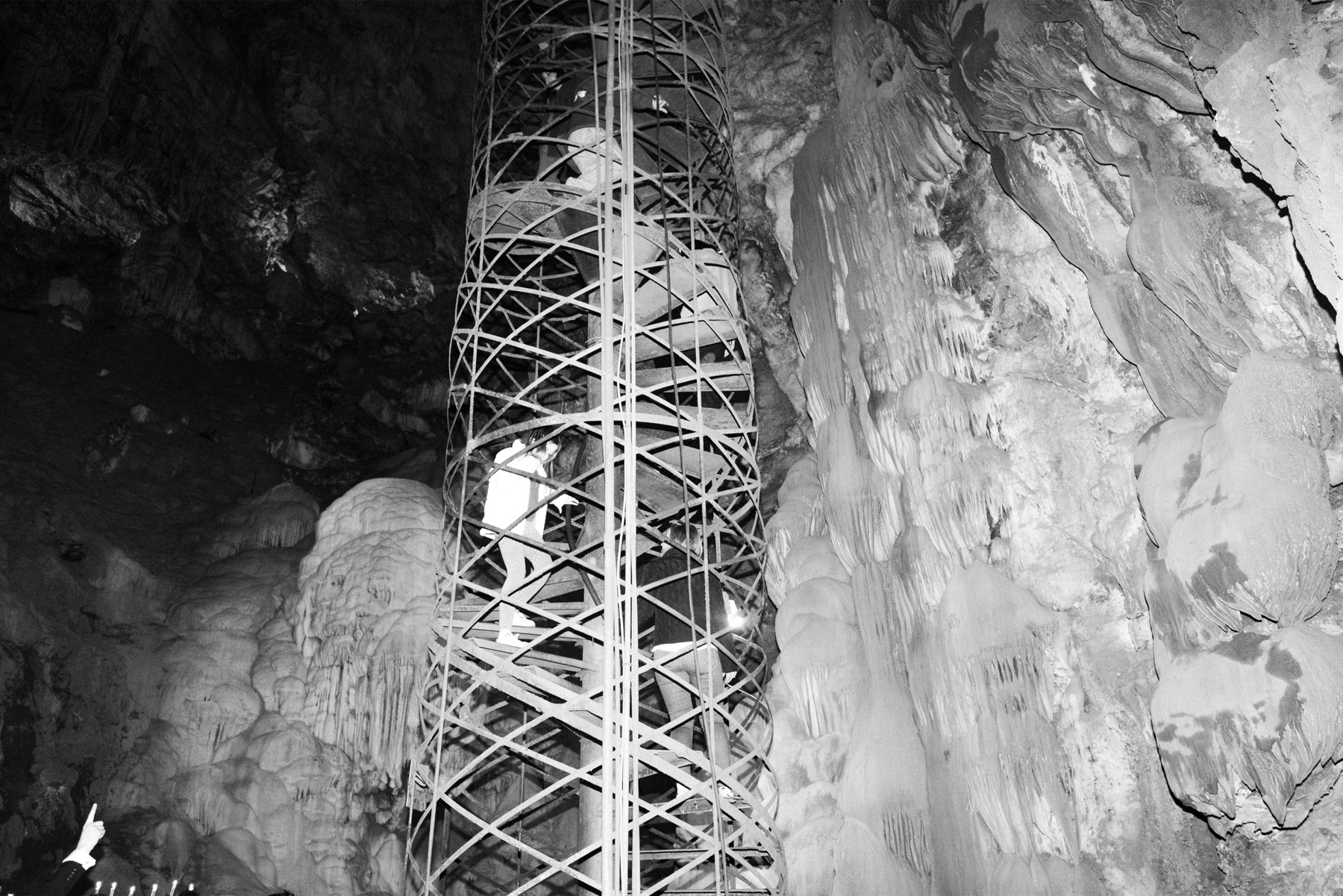 The spiral staircase tower rising between cave formations, with people climbing inside